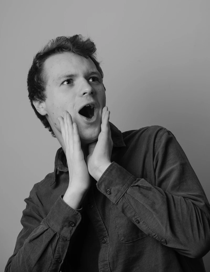 A man pressing both hands to his cheeks with his mouth open, as if in tooth pain